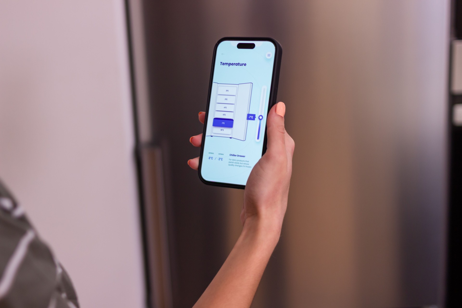 Woman using smart refrigerator app on smartphone controlling temperature